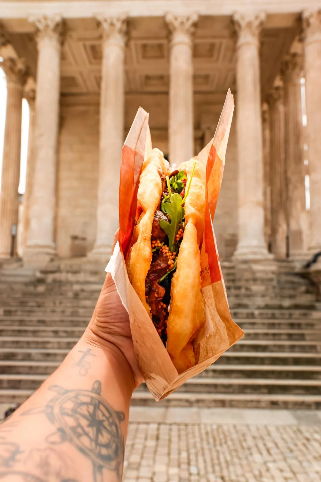 Lángos Mamie Langos devant un monument de Nîmes